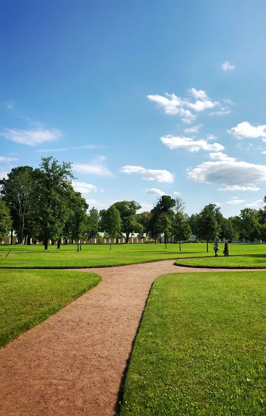 Gepflegter Park mit Rasenflächen und Weg unter blauem Himmel